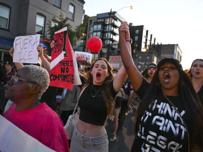 Protesters hold hands and shout slogans as they walk down U Street during an "End the DC Occupation" rally against U.S. President Donald Trump and his use of emergency powers to take over the D..C Police in Washington, D.C., on August 23, 2025.