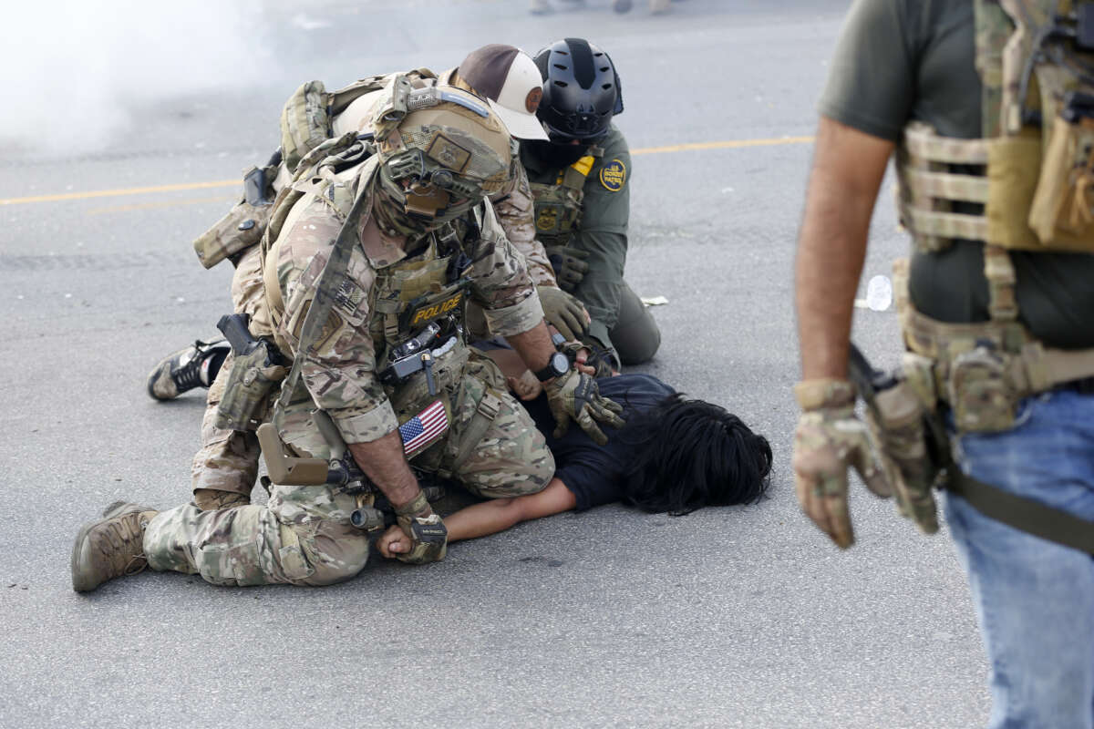 A person is detained as residents of Chicago's Brighton Park neighborhood confront U.S. Border Patrol and other law enforcement agents at a gas station after Immigration and Customs Enforcement (ICE) agents allegedly detained an unidentified man riding in his car, in Chicago, Illinois, on October 4, 2025.