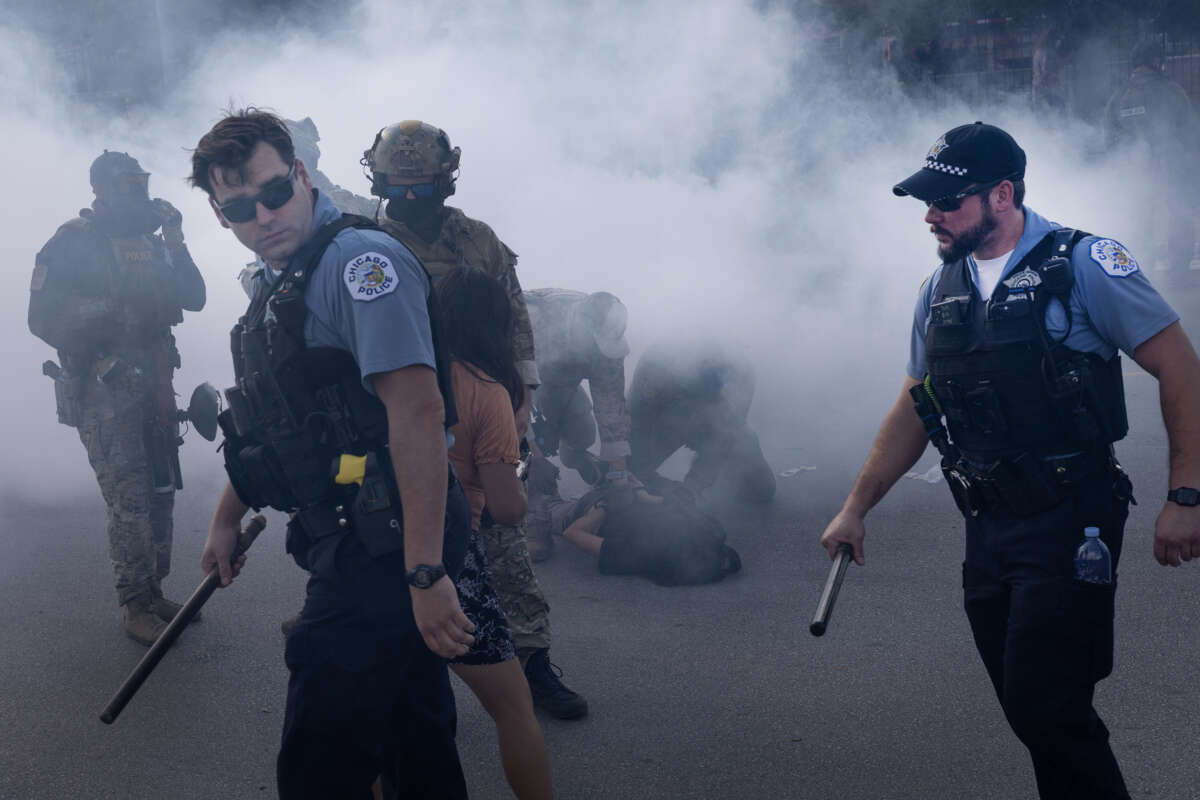 Chicago police officers and federal law enforcement agents stand in a cloud of tear gas deployed by federal agents against protesters in Broadview, Illinois, on October 4, 2025. The protest erupted after a Customs and Border Protection agent shot an anti-ICE protester in Brighton Park.