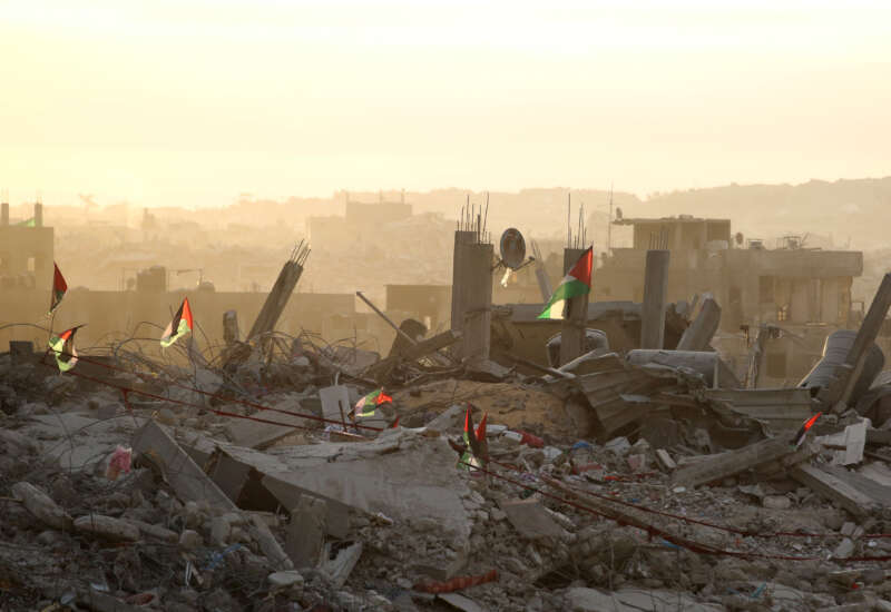 Palestinian flags flutter on top of rubble in Gaza City on October 12, 2025.