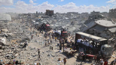 Palestinians rally around aid trucks which entered from the Karem Abu Salem crossing, in Khan Yunis in the southern Gaza Strip, on October 12, 2025.