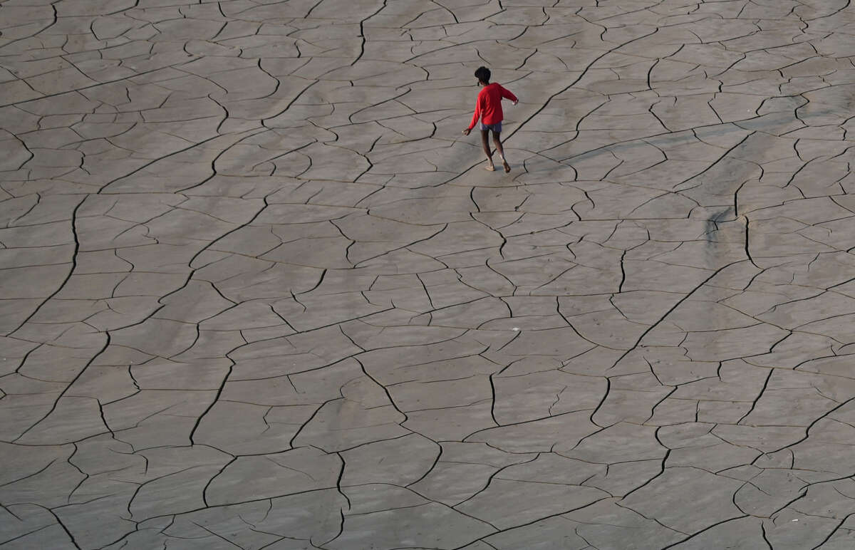 Youths walk along a dry riverbed on the banks of the river Ganges in Prayagraj, India, on October 14, 2025.