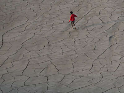 Youths walk along a dry riverbed on the banks of the river Ganges in Prayagraj, India, on October 14, 2025.