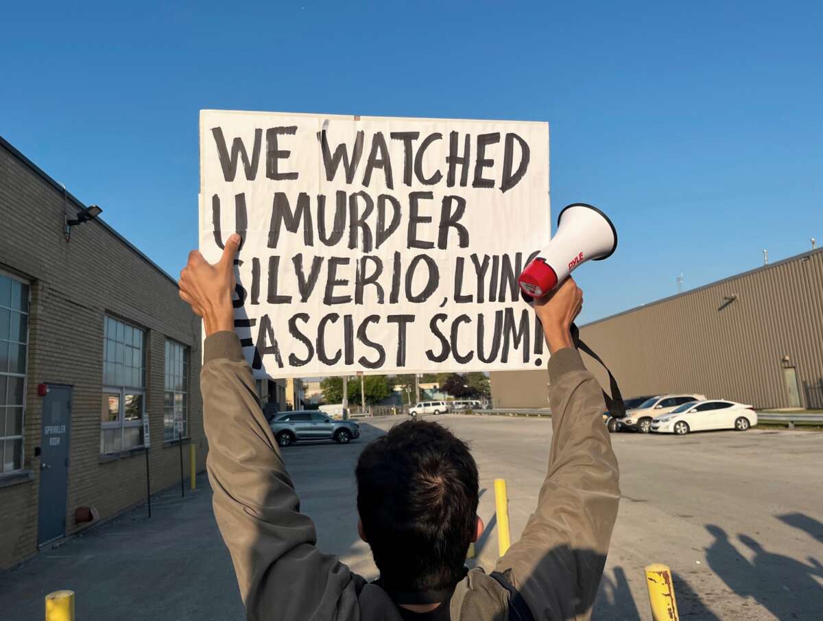 Un manifestante posee una señal que lee "Nos vimos asesinar a Silverio acostado escoria fascista."