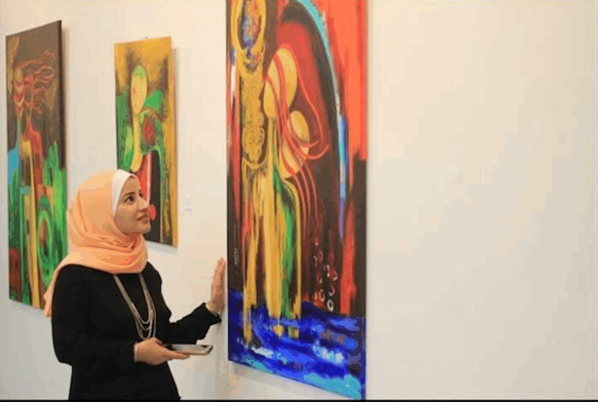 - Bloggizmo.com Awatif Al-Saqqa stands with her art during a private exhibition in Gaza in 2018. “Through my creations, I strive to convey a noble message,” she says. “A message of love, harmony, and peace to the world.”