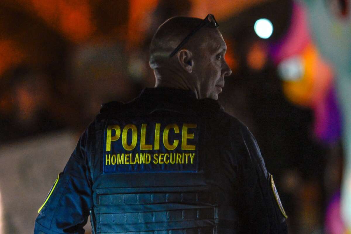 A Department of Homeland Security agent stands guard as protesters demonstrate against recent raids conducted by the US Immigration and Customs Enforcement (ICE) outside the DHS office in Charlotte, North Carolina, on November 16, 2025.