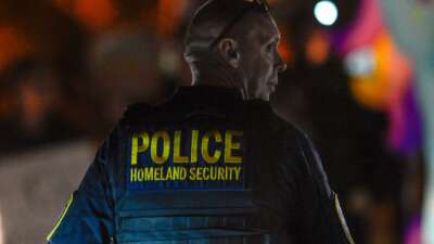 A Department of Homeland Security agent stands guard as protesters demonstrate against recent raids conducted by the US Immigration and Customs Enforcement (ICE) outside the DHS office in Charlotte, North Carolina, on November 16, 2025.