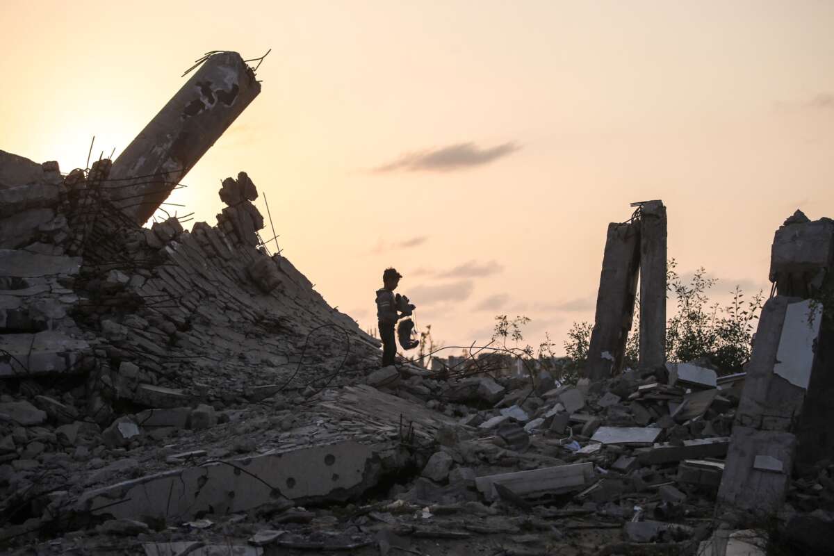 A young Palestinian boy picks up a piece of rubble in Nuseirat, Gaza Strip on November 11, 2025.