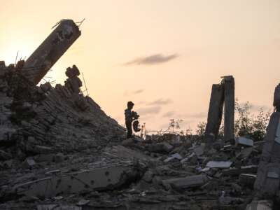 A young Palestinian boy picks up a piece of rubble in Nuseirat, Gaza Strip on November 11, 2025.