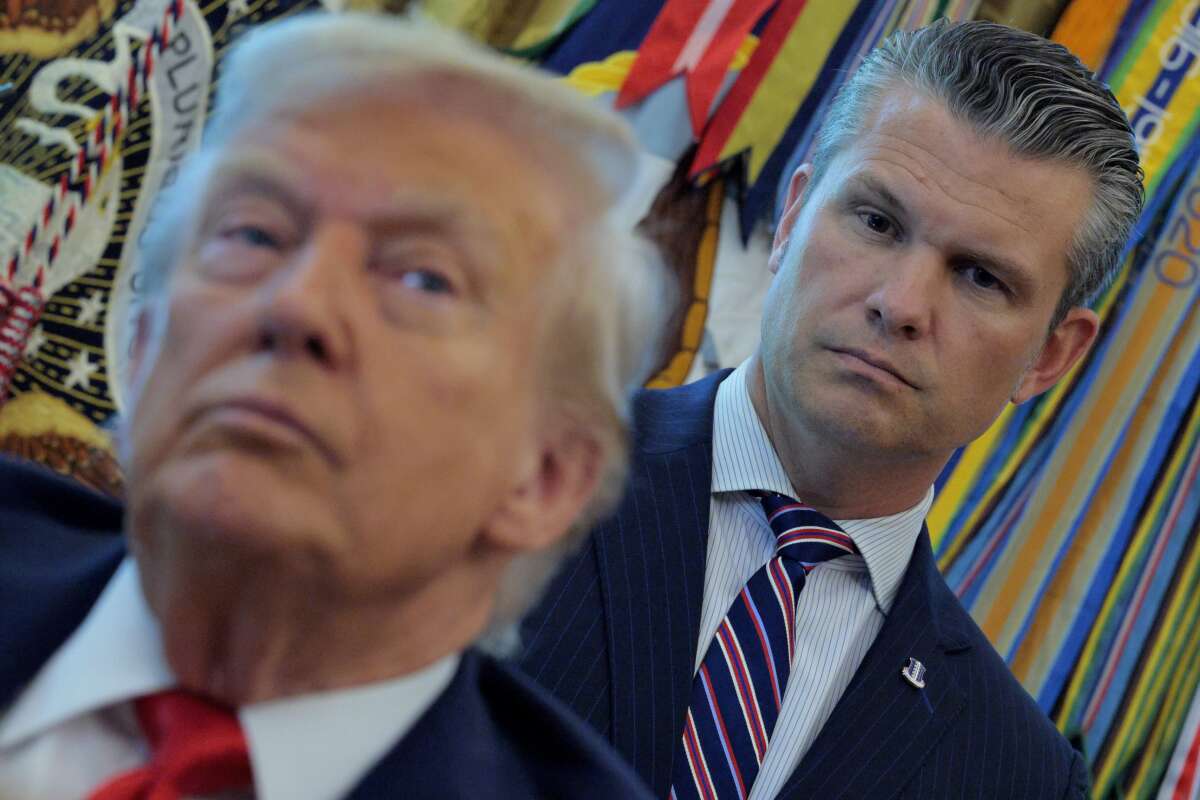 Defense Secretary Pete Hegseth listens to President Donald Trump talk to journalists after signing executive orders in the Oval Office at the White House on August 25, 2025, in Washington, D.C.