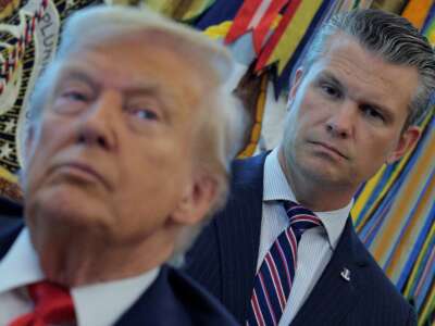 Defense Secretary Pete Hegseth listens to President Donald Trump talk to journalists after signing executive orders in the Oval Office at the White House on August 25, 2025, in Washington, D.C.