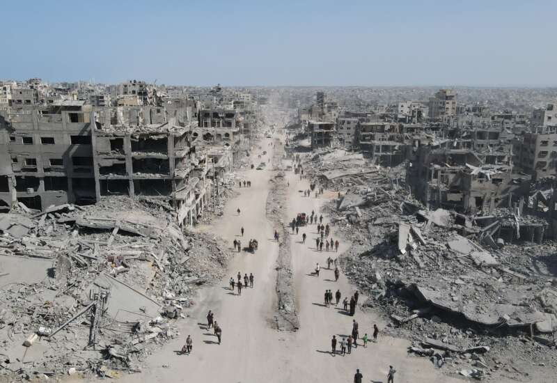 In this aerial view, people walk amid the destruction in Gaza City in the northern Gaza Strip on October 11, 2025, a day after a ceasefire took effect.