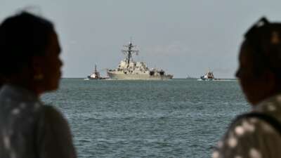 People watch the USS Gravely, a U.S. Navy warship, departing the Port of Spain on October 30, 2025. The warship arrived in Trinidad and Tobago on October 26, 2025, for joint exercises near the coast of Venezuela.