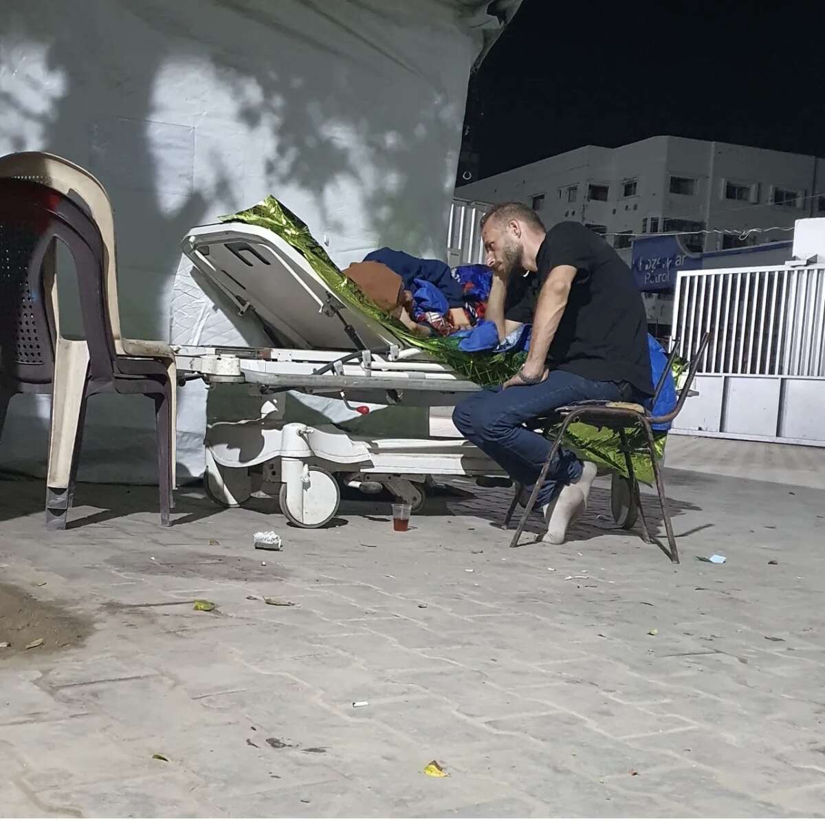 The journalist Wadeaa Abu al-Saoud sits with his ailed wife in the vicinity of Al Shifa Hospital, as the hospital’s corridors were overflowing with casualties.