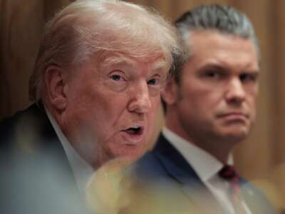 U.S. Secretary of War Pete Hegseth (R) looks on as U.S. President Donald Trump speaks during a meeting of his Cabinet in the Cabinet Room of the White House on December 2, 2025 in Washington, D.C.