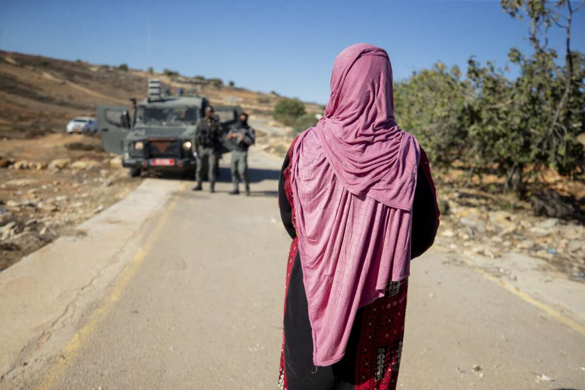 Israeli border guards approach a Palestinian woman on a rural road near olive groves in Ramallah in the Israeli-occupied West Bank, on October 27, 2025. With the olive harvest season starting in October, farmers in the region are frequently subject to attacks by Israeli settlers.