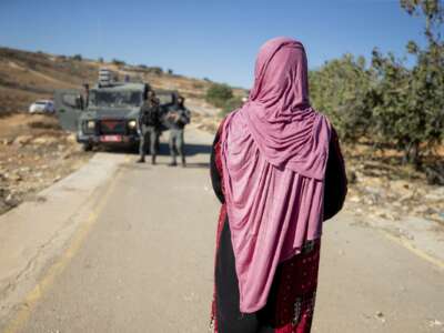 Israeli border guards approach a Palestinian woman on a rural road near olive groves in Ramallah in the Israeli-occupied West Bank, on October 27, 2025. With the olive harvest season starting in October, farmers in the region are frequently subject to attacks by Israeli settlers.