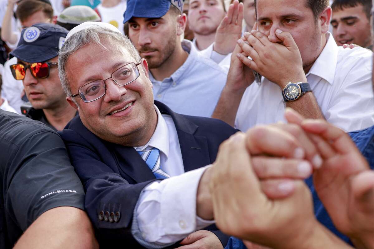 Israeli Minister of National Security and far-right politician Itamar Ben-Gvir reaches out to a supporter as he walks escorted by Israeli policemen outside the Damascus Gate of the walled Old City of Jerusalem on May 26, 2025, during a flag march for Jerusalem Day, commemorating the Israeli army's 1967 capture of the city's eastern sector during the Arab-Israeli war.