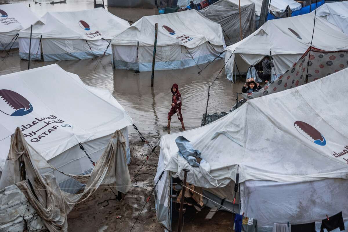 A boy walks through a waterlogged alley at a makeshift camp sheltering displaced Palestinians after heavy rains in the Zeitoun neighborhood of Gaza City on December 11, 2025.