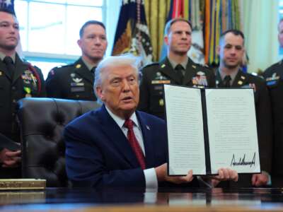 President Donald Trump poses with a recently signed executive order classifying fentanyl as a "weapon of mass destruction," during a ceremony for the presentation of the Mexican Border Defense Medal in the Oval Office of the White House on December 15, 2025 in Washington, D.C.