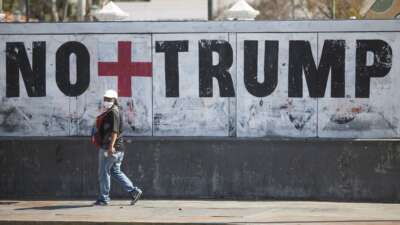 A woman walks past graffiti against U.S. President Donald Trump on March 26, 2020, in Caracas, Venezuela.