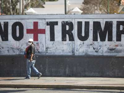 A woman walks past graffiti against U.S. President Donald Trump on March 26, 2020, in Caracas, Venezuela.