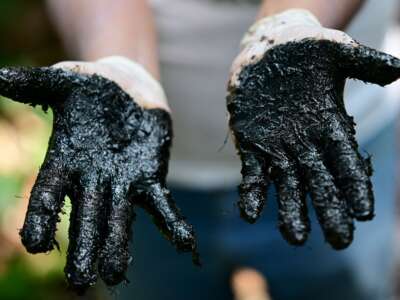 Ecuadorian activist Donald Moncayo Jimenez, chief coordinator of the Union of People Affected by Chevron-Texaco, shows his hands with hydrocarbon waste over an outdoor pool that was used in the process of drilling of the Aguarico 4 oil well, during a tour of the areas affected by the Chevron/Texaco oil company, in Lago Agrio, in the Sucumbíos Province, Ecuador, on January 14, 2023.