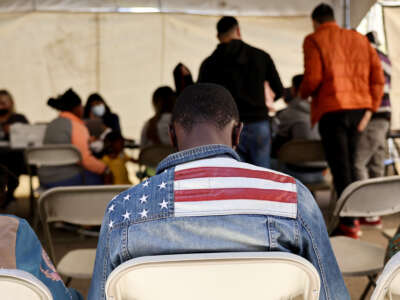 An immigrant from Ghana wears an American flag jacket at a migrant transition center for asylum seekers released from Border Patrol custody, after crossing into the United States, on May 12, 2023, in Somerton, Arizona.