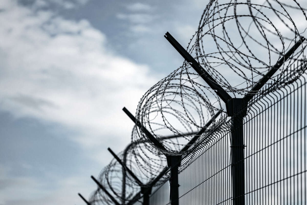 Barbed Wire Fence. Prison or border fence with razor wire against dark sky.
