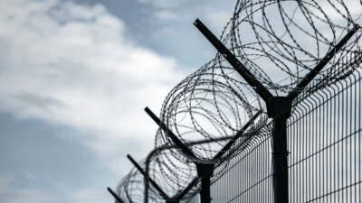 Barbed Wire Fence. Prison or border fence with razor wire against dark sky.