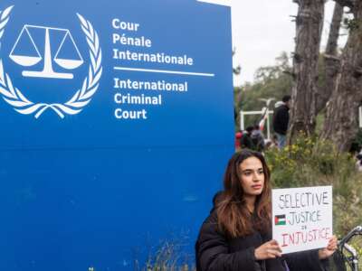 A pro-Palestinian demonstrator holds a sign that reads “Selective Justice Is Injustice” during a pro-Palestine demonstration in front of the International Criminal Court on October 18, 2023, in The Hague, Netherlands.