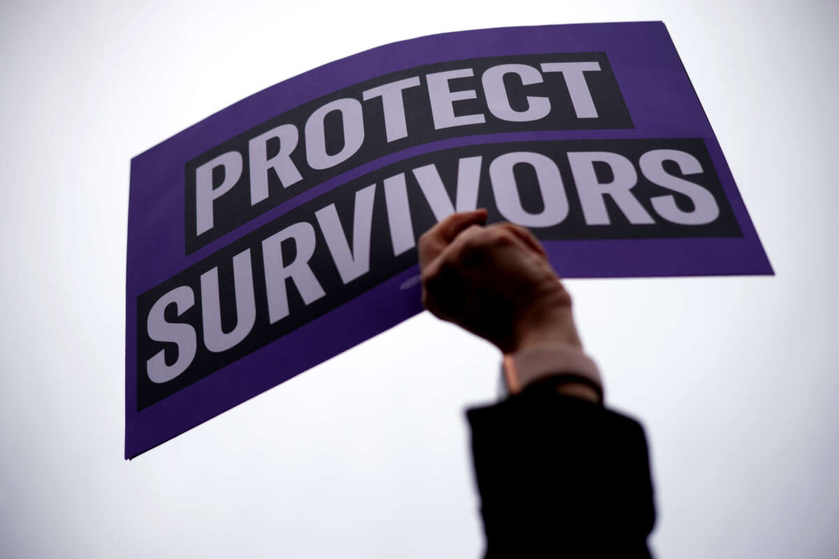 An activist holds up a “Protect Survivors” sign at a rally in Washington, D.C., in November 2023.