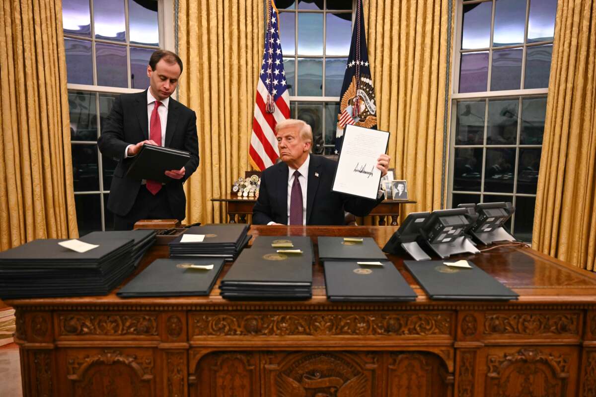 Donald Trump signs executive orders in the Oval Office of the White House in Washington, D.C., on January 20, 2025. A Department of Justice memo dated December 2, 2025, says certain standards under the Prison Rape Elimination Act do not align with an anti-trans executive order that Trump signed on January 20.