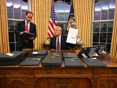 Donald Trump signs executive orders in the Oval Office of the White House in Washington, D.C., on January 20, 2025. A Department of Justice memo dated December 2, 2025, says certain standards under the Prison Rape Elimination Act do not align with an anti-trans executive order that Trump signed on January 20.