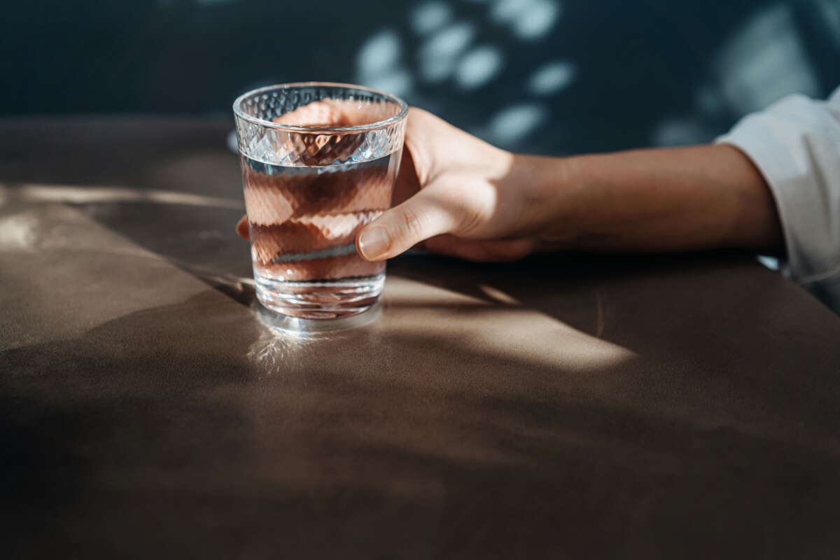 Close-up shot of a young woman's hand holding a glass of water.