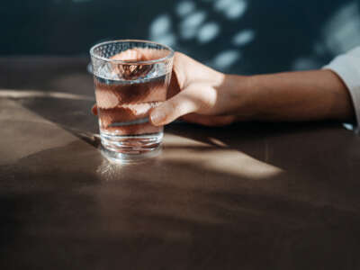 Close-up shot of a young woman's hand holding a glass of water.