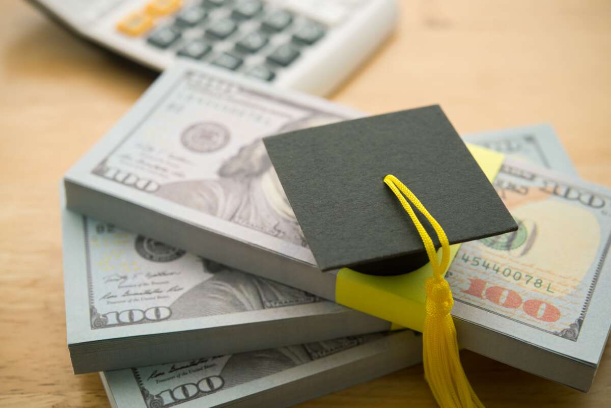 Graduation cap on stack US banknotes