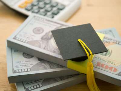 Graduation cap on stack US banknotes