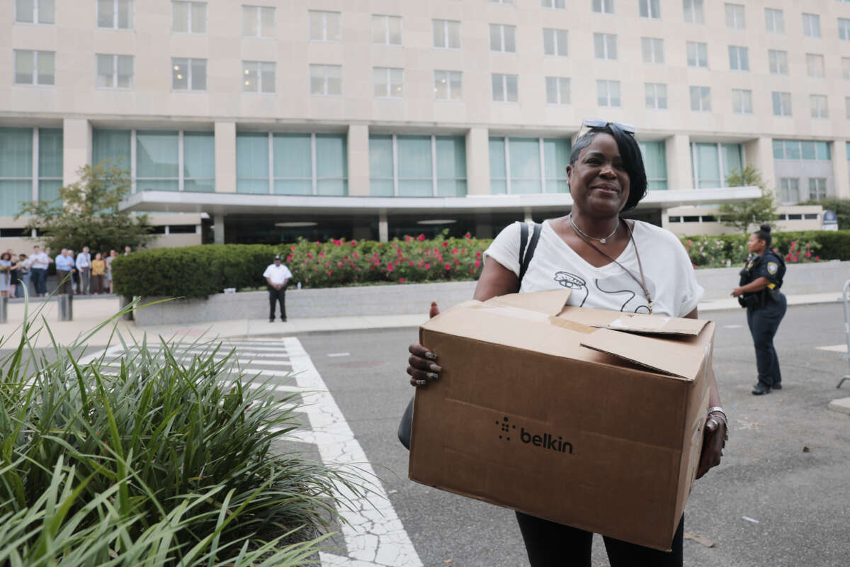 Recently laid off U.S. State Department employees carry boxes as they walk out of the Harry S. Truman Federal Building on July 11, 2025, in Washington, D.C.