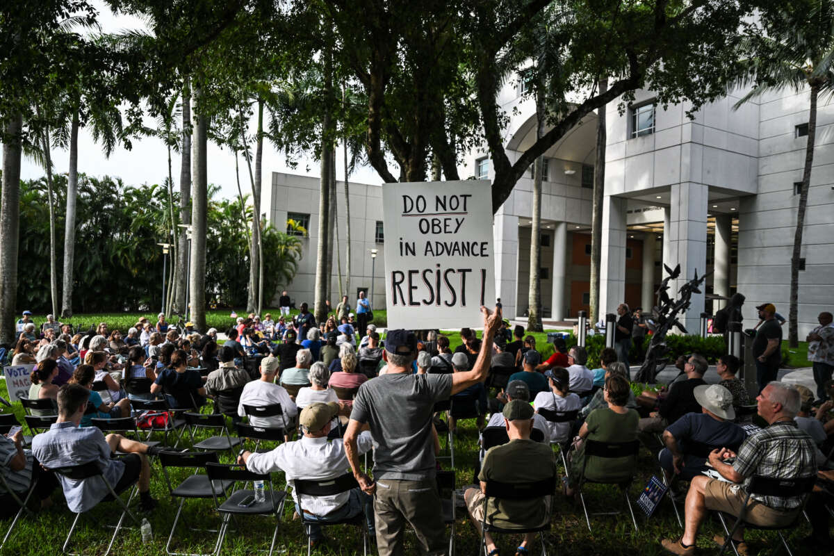 A man holds up sign reading "Do Obey in Advance, Resist" during a protest as part of the 'Good Trouble Lives On' national day of action against the administration of U.S. President Donald Trump at Florida International University Green Library in Miami, Florida, on July 17, 2025.