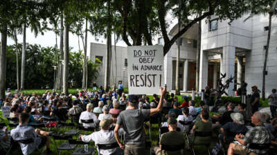 A man holds up sign reading "Do Obey in Advance, Resist" during a protest as part of the 'Good Trouble Lives On' national day of action against the administration of U.S. President Donald Trump at Florida International University Green Library in Miami, Florida, on July 17, 2025.