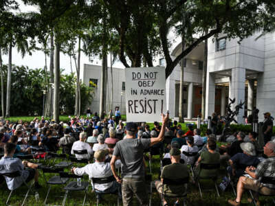 A man holds up sign reading "Do Obey in Advance, Resist" during a protest as part of the 'Good Trouble Lives On' national day of action against the administration of U.S. President Donald Trump at Florida International University Green Library in Miami, Florida, on July 17, 2025.