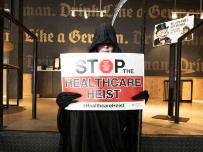 Priya Telang sits with a card regarding Healthcare cuts and ACA on the first day of open enrollment during the Don’t Let the Ghouls Gut Our Healthcare! event on November 1, 2025, in Northglenn, Colorado.