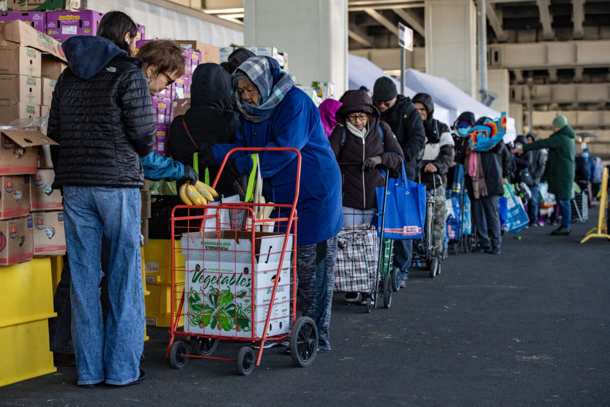 Workers and volunteers hand out food to people in line at La Colaborativa's food pantry in Chelsea, Massachusetts, on November 15, 2025.