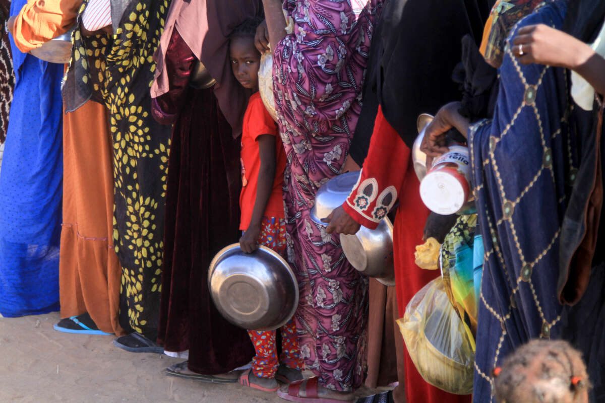 A Sudanese girl who fled El-Fasher lines up with other women to receive a free meal at the Al-Afad camp for displaced people in the town of Al-Dabba, Sudan, on November 20, 2025.