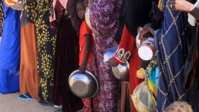 A Sudanese girl who fled El-Fasher lines up with other women to receive a free meal at the Al-Afad camp for displaced people in the town of Al-Dabba, Sudan, on November 20, 2025.
