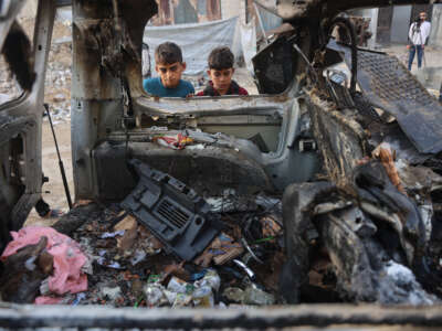 Palestinian displaced children look at a destroyed vehicle targeted by the Israeli military, in Gaza City, on November 22, 2025.