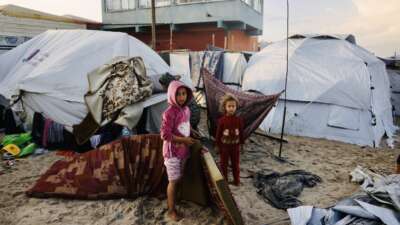 Palestinian children move mattresses to protect them from the rain at a makeshift camp housing displaced Palestinians in Deir al-Balah, in the central Gaza Strip, on November 25, 2025. With many displaced living in tent camps, the coming winter is raising serious concerns.