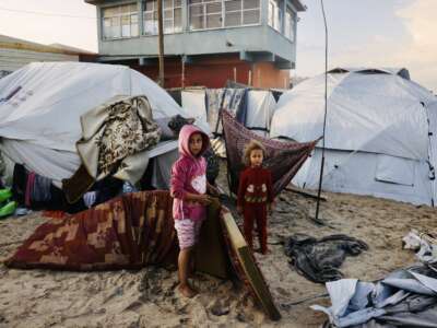 Palestinian children move mattresses to protect them from the rain at a makeshift camp housing displaced Palestinians in Deir al-Balah, in the central Gaza Strip, on November 25, 2025. With many displaced living in tent camps, the coming winter is raising serious concerns.