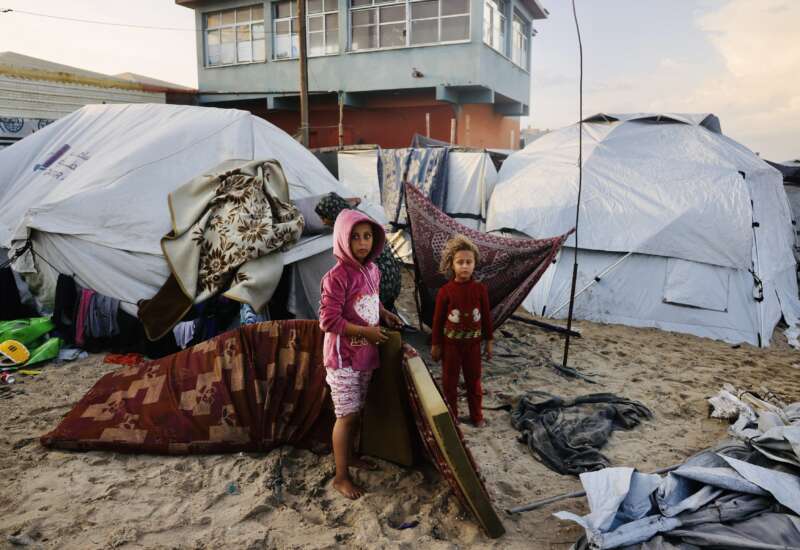 Palestinian children move mattresses to protect them from the rain at a makeshift camp housing displaced Palestinians in Deir al-Balah, in the central Gaza Strip, on November 25, 2025. With many displaced living in tent camps, the coming winter is raising serious concerns.